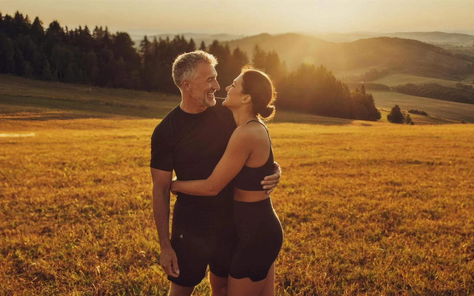 A couple embracing in a golden meadow at sunset