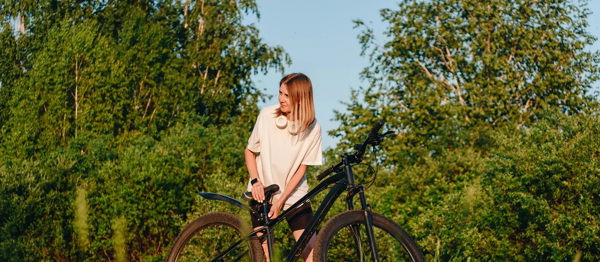 A woman with her bicycle in a wildflower meadow at golden hour