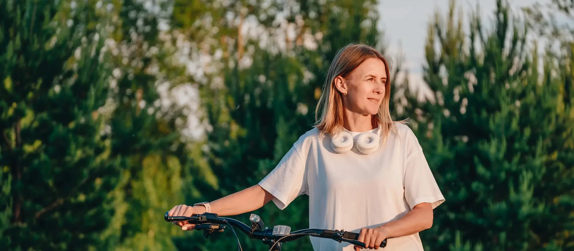 A woman pausing with her bicycle in the evening light