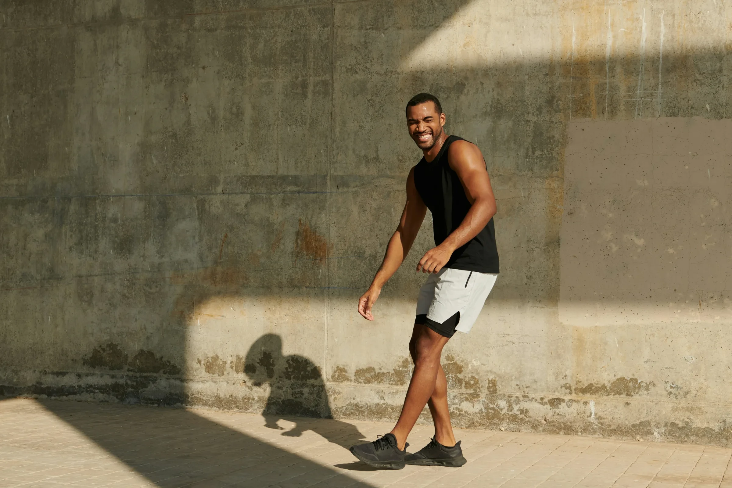 A man mid-stride, laughing in warm sunlight